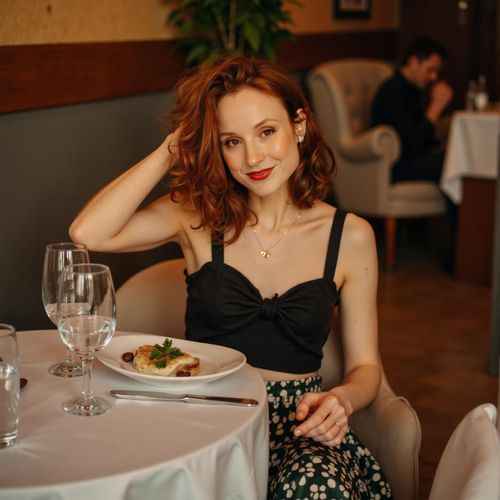 Showcase image for Date Night - Prompt: a photo of me WOMAN at a nice restaurant, half body shot, smart casual attire, warm lighting. WOMAN looking engagingly at the camera.