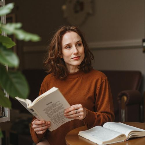 Showcase image for Intellectual Vibe - Prompt: a photo of me WOMAN engrossed in a book at a cozy cafe, medium shot, looking contemplative. WOMAN looking up thoughtfully.