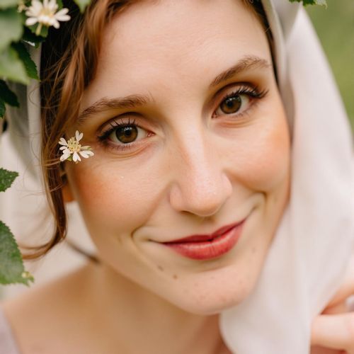 Showcase image for Elegant Details - Prompt: a photo of WOMAN on their wedding day, close-up, holding a single perfect flower near their face, soft lighting. WOMAN with a gentle, happy expression.
