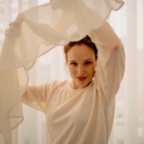 Showcase image for Ethereal Glow - Prompt: a photo of me WOMAN in flowing, light-colored fabric, half body shot, soft, diffused lighting creating an ethereal glow. WOMAN with a serene, dreamy expression.