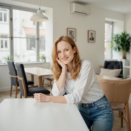 Showcase image for Collaborative Space - Prompt: a photo of me WOMAN in a bright, open-plan office, medium shot, leaning against a communal table. WOMAN looking friendly and collaborative.