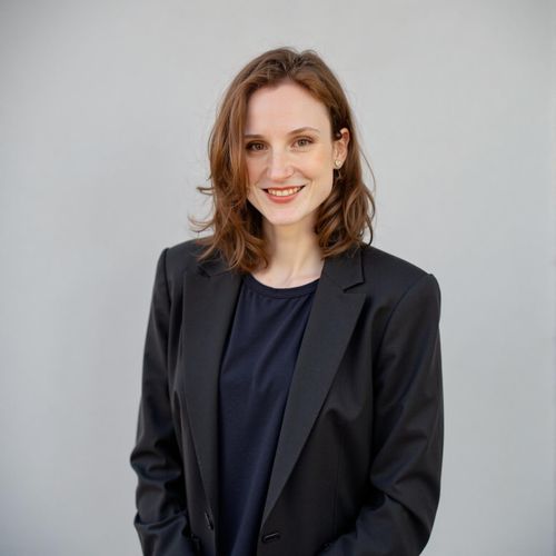 a photo of me WOMAN in a sharp business suit, classic headshot, plain studio background, looking confident. WOMAN making direct eye contact.